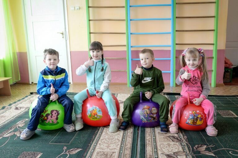 Four children enjoying an indoor play session on colorful bouncing balls. Smiling and having fun.