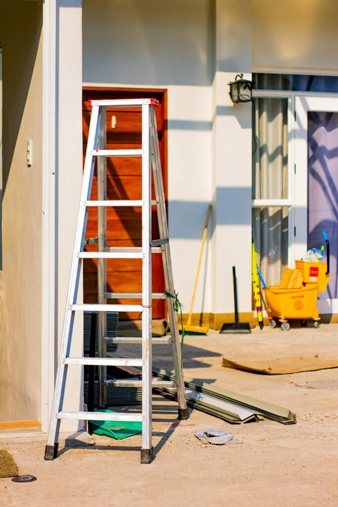 An outdoor home renovation scene featuring a ladder and various tools indicating ongoing construction work.